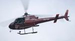 Helikopterin oviaukossa istuu köytettynä kameramies