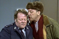 Kuva: Reinikainen puhuu kovaa poliisin korvaan. YLE kuvanauha. 