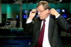 Kuva: Uutisjuontaja Arvi Lind asettaa korvanapin paikoilleen (1999). YLE kuvanauha.