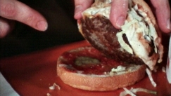 Kuva: Toimittaja Jaakko Kyl�salo esittelee kerroshampurilaista. Kuva: YLE / kuvanauha