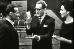 Kuva: Niilo Tarvaj�rvi ja Lenita Airisto tarjoavat kilpailijalle rahaa Laatikkoleikiss�. YLE kuvanauha.