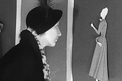 Kuva: Nainen tarkastelee miniatyyrikokoista muotinukkea. YLE kuvanauha.