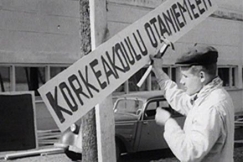 Kuva: Opiskelija naulaa Korkeakoulu Otaniemeen -kyltti� puuhun. YLE kuvanauha.