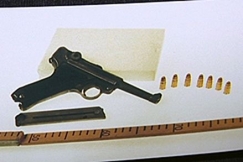 Kuva: Ase, luoteja ja mittanauha. YLE kuvanauha.