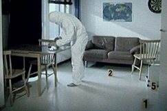 Kuva: Tutkija suojapuvuissa asunnossa. YLE kuvanauha. 