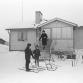 Äiti ja lapset lähtevät omakotitalon pihalta potkukelkoilla. Kalle Kultala, 1960